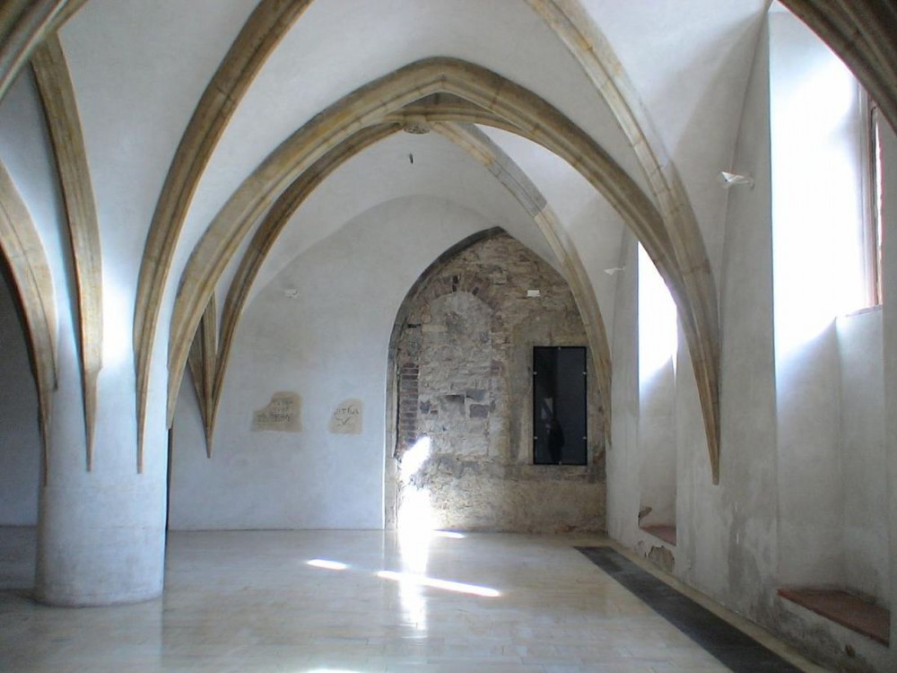 Готический колонный зал со сводом, каменным полом и остатками оригинальных рисунков на стенах.